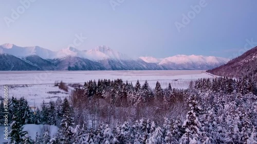 Ariel push over snow covered trees with highway and mountains photo