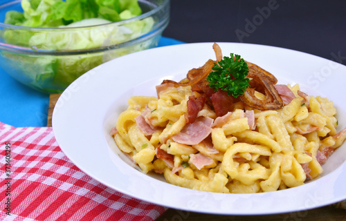 Spätzel or Spaetzel or soft egg noodle fried with ham ,cheese and Topped with fried onions and bacon.