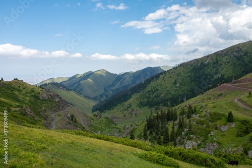 Beautifu lview of green mountains with dangerous gravel road. Ketmen or Ketpen mountains gorge and mountain pass. Tourism in Kazakhstan.