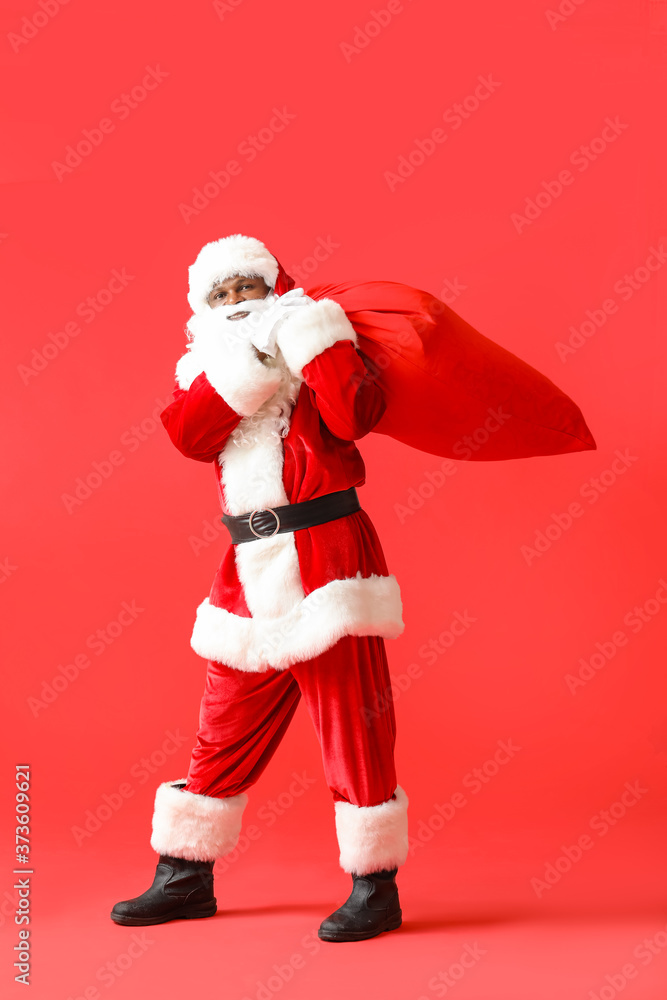 African-American Santa Claus with bag on color background African-American Santa Claus with bag on color background