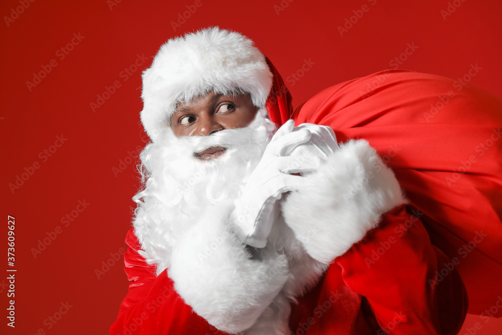 African-American Santa Claus with bag on color background African-American Santa Claus with bag on color background