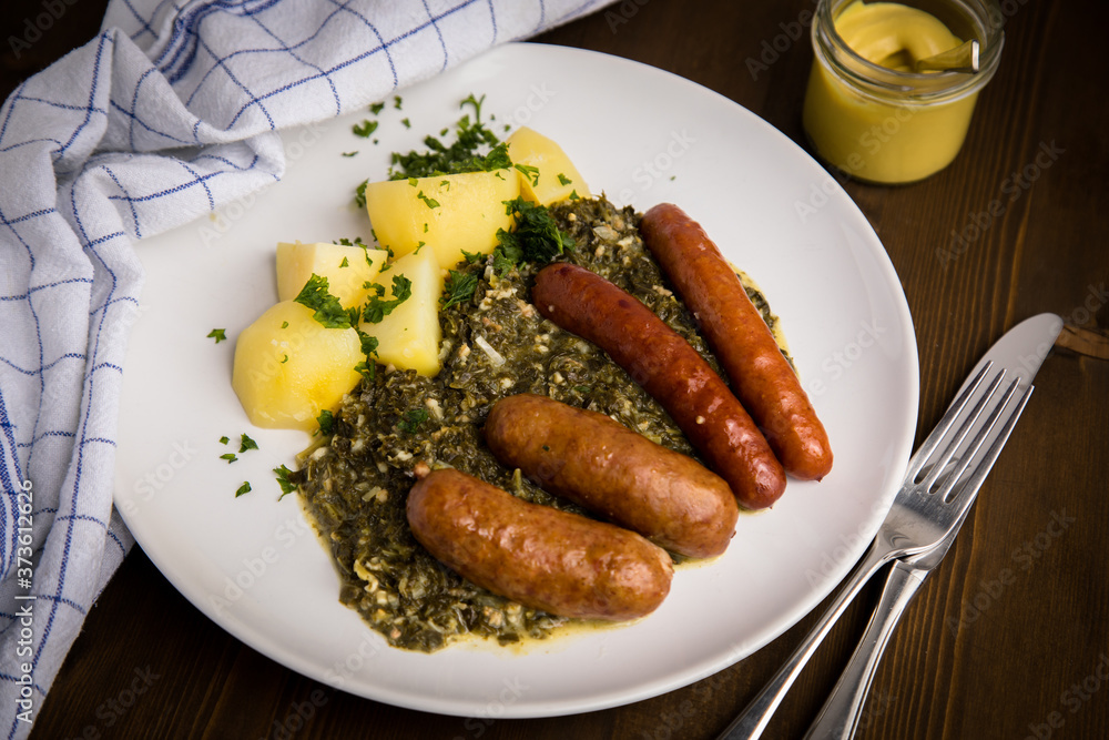 Oldenburger Grünkohl mit Pinkel, Kohlwurst, Senf und Kartoffeln auf Holz Tisch Oldenburger Grünkohl mit Pinkel, Kohlwurst, Senf und Kartoffeln auf Holz Tisch