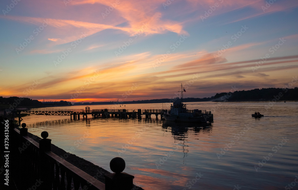 Small boat at the river pier against the background of the sunset Small boat at the river pier against the background of the sunset