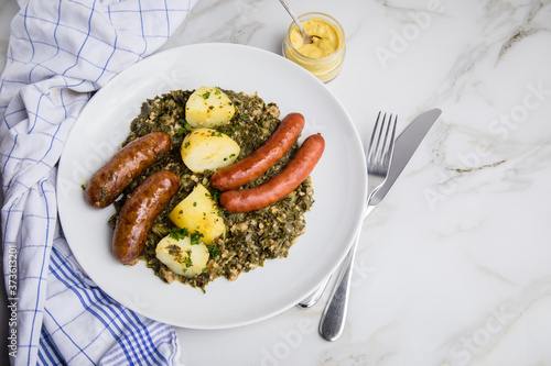 Oldenburger Grünkohl mit Pinkel, Kohlwurst, Senf und Kartoffeln auf Marmor Tisch