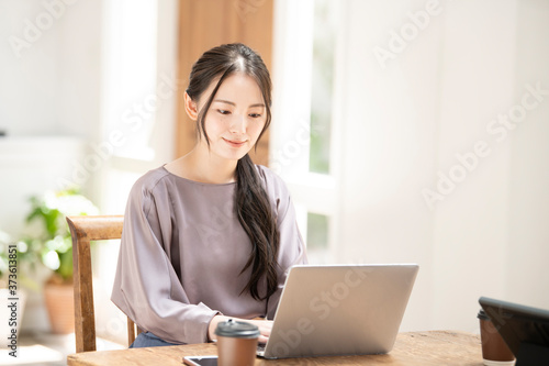 パソコンを使いながらZoomなどでリモートワークのミーティングの準備をするうつむく美しい若い日本人女性コピースペースあり2