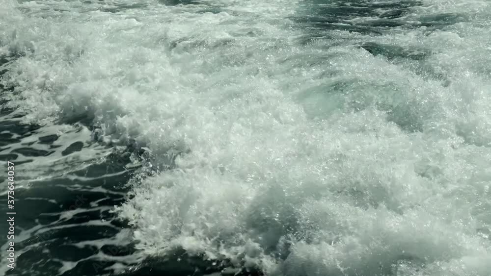 Slow motion. Looking at the foaming trail in the water left by the speeding yacht. Scenic view of the tropical seascape. Sea foam. The waves.