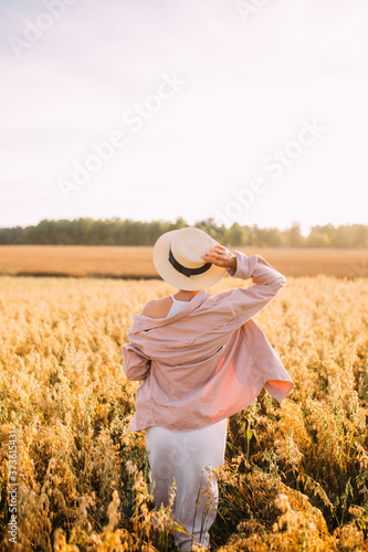 a girl in a straw hat with her back to the field