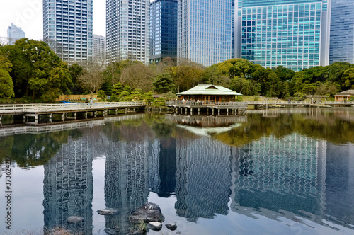 Traditional Japanese tea house in the park in front of urban view of modern skyscrapers with beautiful water reflection in the pond water, old and new concept photo