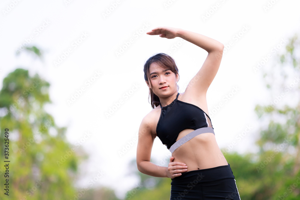 Active female raising left arms while standing during fitness or yoga practice. One young woman practicing yoga outdoors in garden. Healthy life and natural balance between body and mental development Active female raising left arms while standing during fitness or yoga practice. One young woman practicing yoga outdoors in garden. Healthy life and natural balance between body and mental development