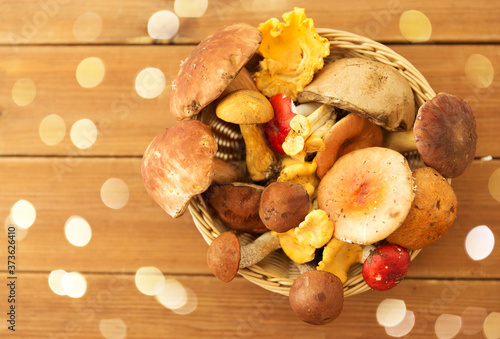 nature, environment and harvest concept - basket of different edible mushrooms on wooden table