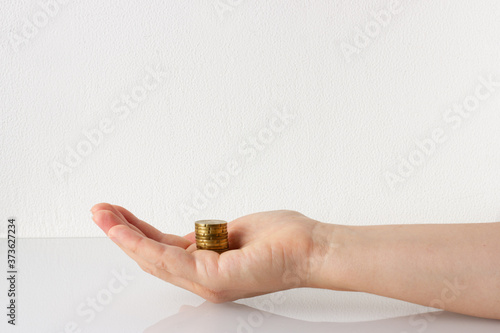 Money, stack of coins on hand. Donation, charity, finance or investment concept. White background, copy space.