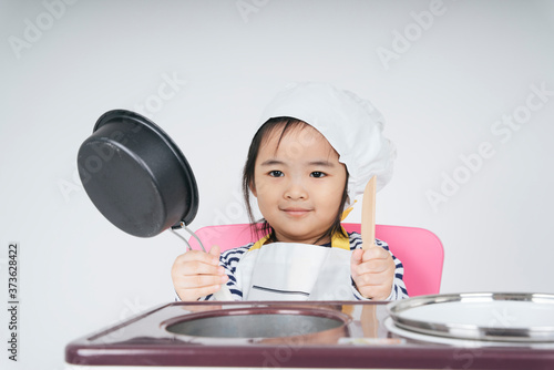 Asian thai kid play role as a chef working at cooker station with boil pot.