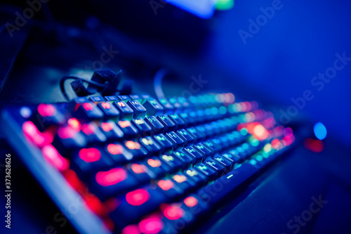 Professional cyber video gamer studio room with personal computer armchair, keyboard for stream in neon color blur background. Soft focus