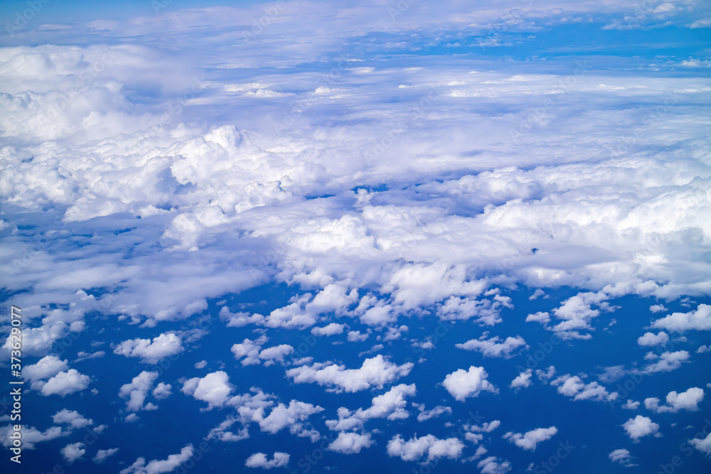 Floating clouds in the blue sky, view from airplane