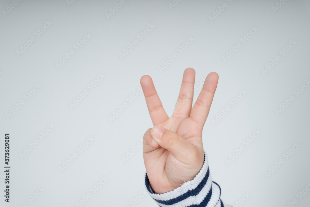 © THESHOTS.CO - Kid hand with three fingers gesture. © THESHOTS.CO - Kid hand with three fingers gesture.