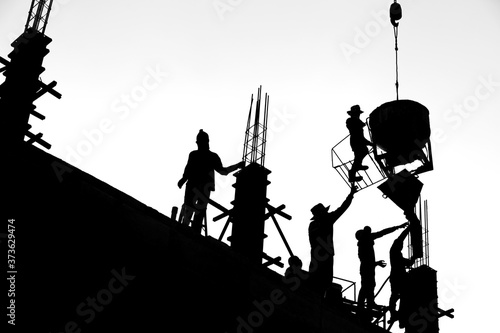 Construction workers are casting columns to build buildings using cranes. It is a black and white style picture.