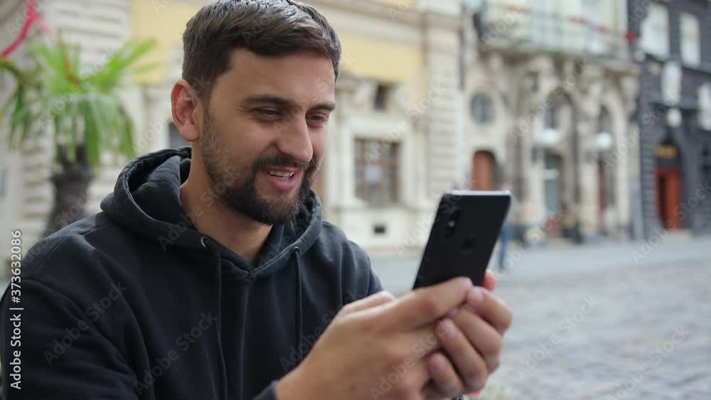 Portrait of business man reading message with smart phone in outdoor. Using smartphone for video calls. Looking at screen, smiling, gesturing. Connection concept. Close up businessman having chat Portrait of business man reading message with smart phone in outdoor. Using smartphone for video calls. Looking at screen, smiling, gesturing. Connection concept. Close up businessman having chat