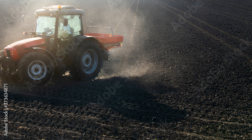 Tractor spreading artificial fertilizers in field © Dusan Kostic