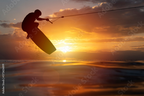 Tableau sur toile Silhouette male athlete trains wakeboard extreme water sport jumping from the ra