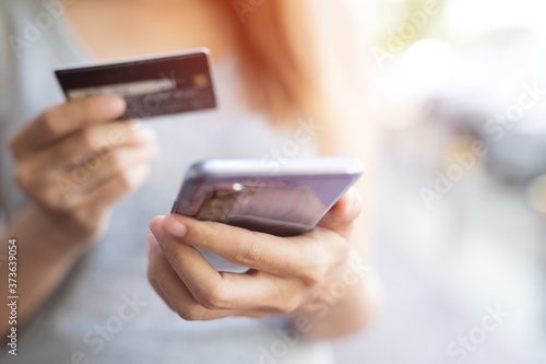 Fototapeta Naklejka Na Ścianę i Meble -  Close up of woman hands holding smart phone and and using cell credit card for online shopping payment.