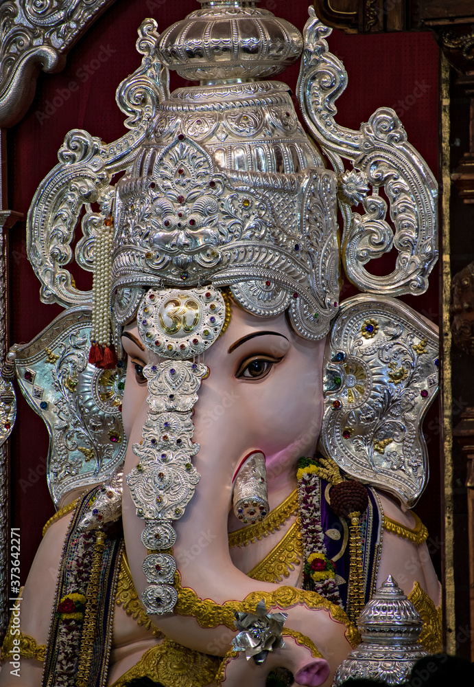 Obraz premium Close up portrait view of decorated and garlanded idol of Hindu God Ganesha.