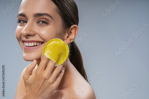 Beautiful lady with a beaming smile exfoliating her skin
