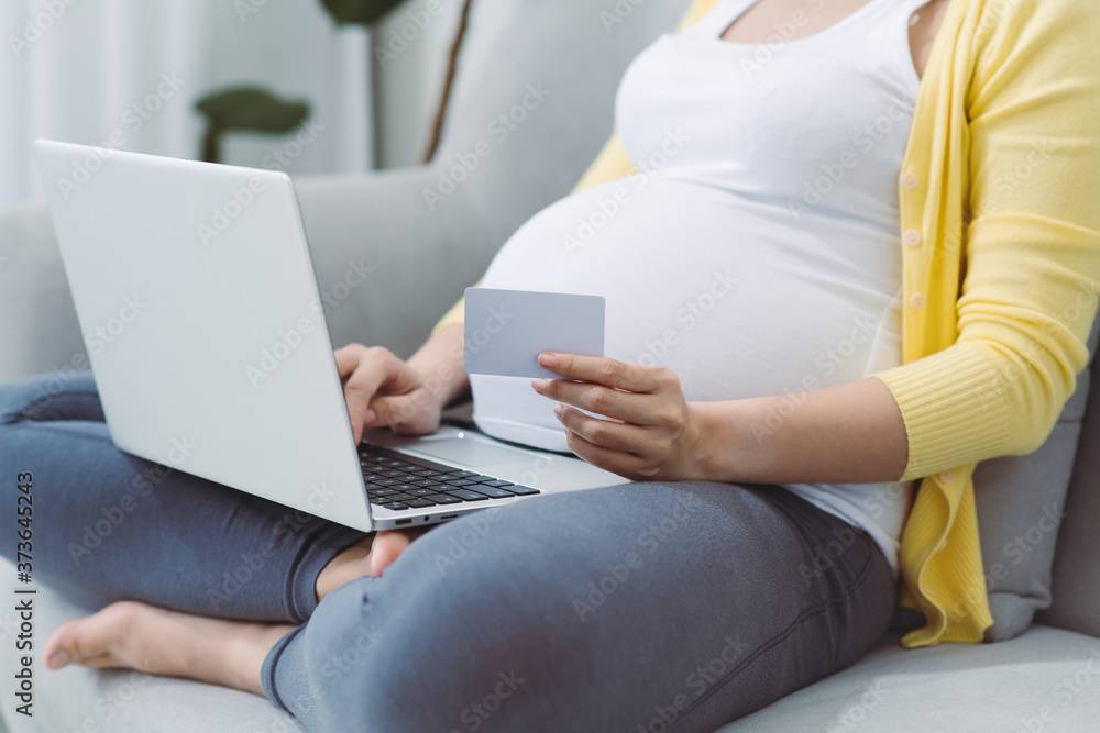 Naklejka premium Happy pregnant woman pays order with credit card in online store at home. Online shopping