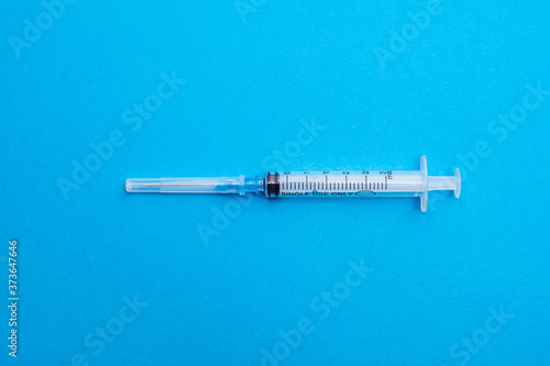 Medical syringe isolated on a blue background close-up. Minimalistic. The view from the top. Concepts of medicine. Antibiotics, painkillers, vitamins. Concept of different treatment methods