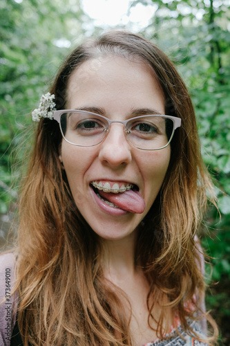 portrait of a young woman making funny faces with a flower in her hair