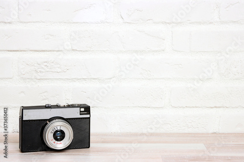 Old retro camera agianst white brick wall. photo