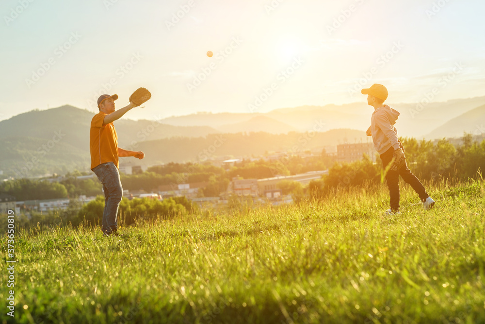 Father and son playing in baseball. Playful Man teaching Boy baseballs exercise outdoors in sunny day at public park. Family sports weekend. Father's day. Father and son playing in baseball. Playful Man teaching Boy baseballs exercise outdoors in sunny day at public park. Family sports weekend. Father's day.