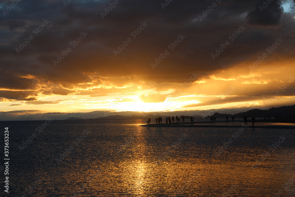 Sunset view of Namtso lake with the human silhouette and dramatic sky, Tibet, China