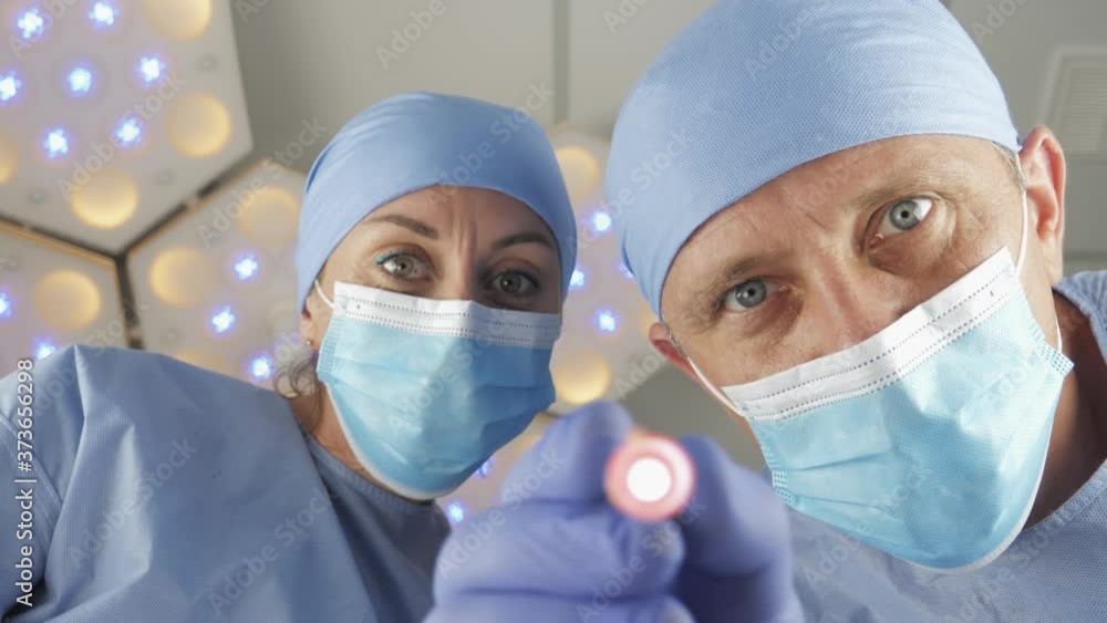 Doctor surgeon with assistant checks the reaction of the pupils of the ...