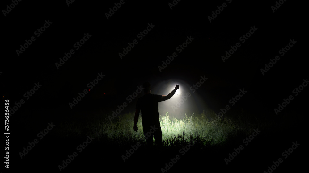 Person with flashlight at night - obrazy, fototapety, plakaty 