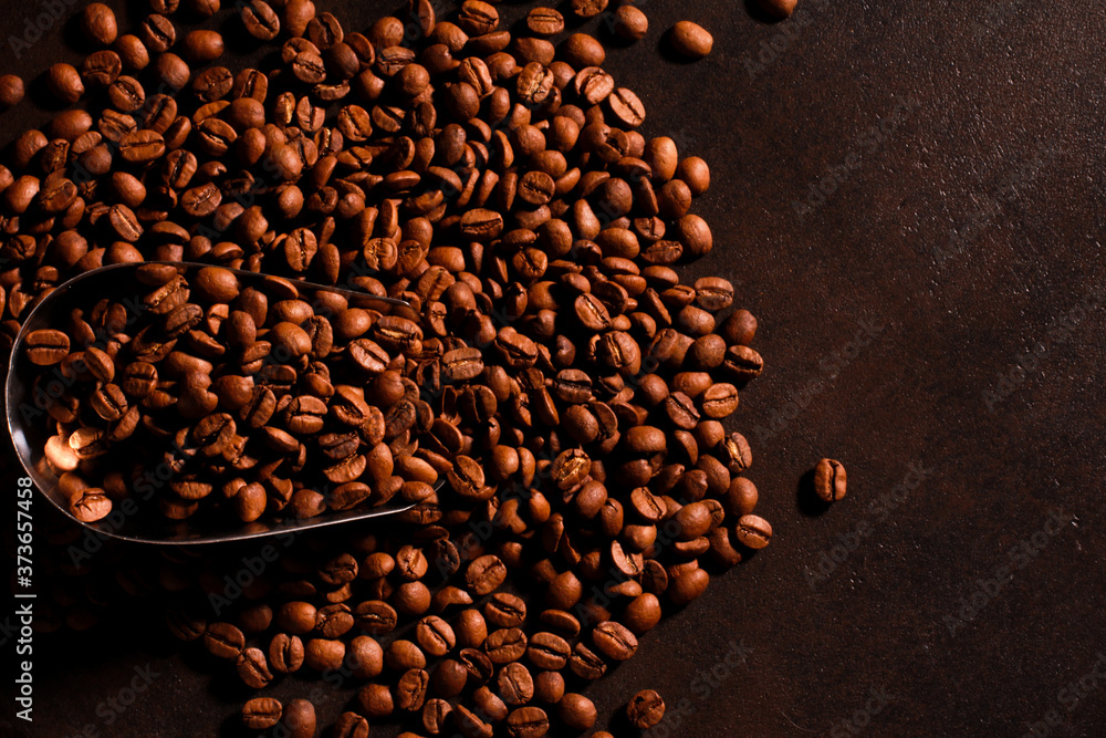 Arabica Coffee beans scattered from metal scoop on dark background. Roasted grains, copy space. Coffee shop, caffeine, roast concept Arabica Coffee beans scattered from metal scoop on dark background. Roasted grains, copy space. Coffee shop, caffeine, roast concept