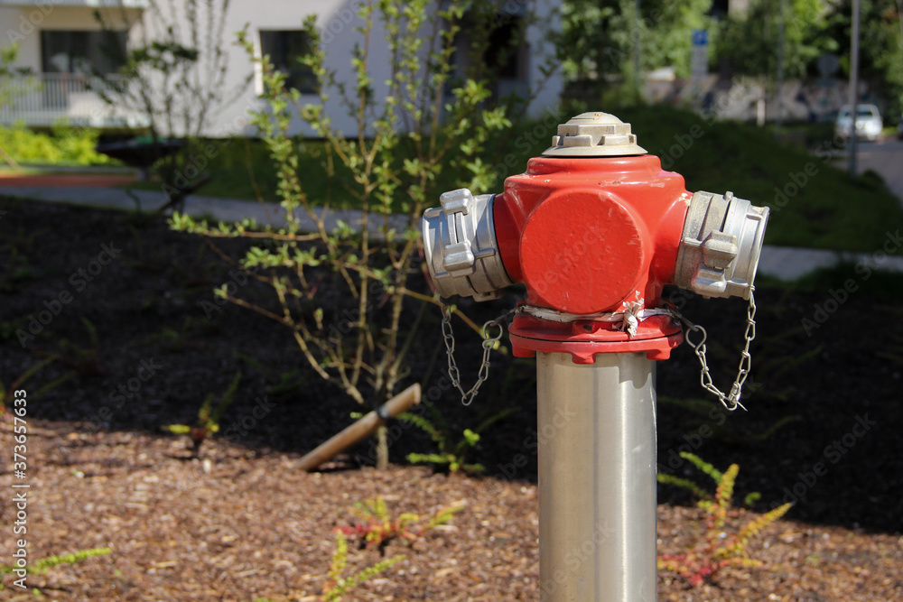 Painted steel hydrant stands on the lawn of a multistorey apartment. Fire hydrant at a public place. Painted steel hydrant stands on the lawn of a multistorey apartment. Fire hydrant at a public place.