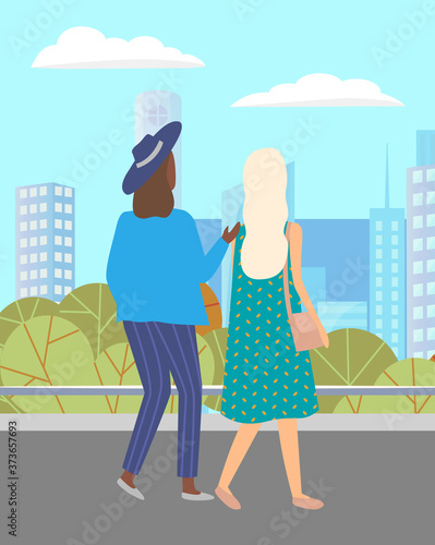 Women walking down the street. Meeting of girlfriends outdoor. Two friends women walking in city against the background of the cityscape of tall buildings. Female with bag and in hat summertime