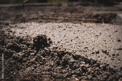 Close-up of wet cement solution poured on reinforcing metal bars on construction site  engineering concept