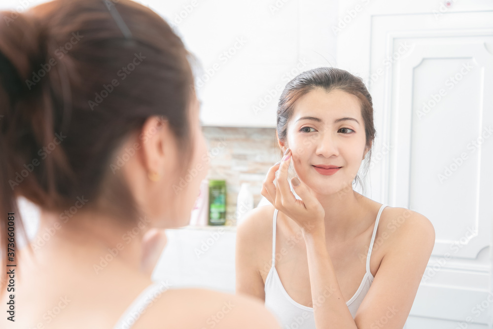 Asian Beauty Woman apply face cream in bathroom.