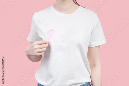 World Breast cancer day concept. Woman in white T-shirt holds pink ribbon in her hand. October Breast Cancer Awareness month