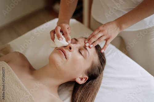 Cosmetologist Wiping Client Face after Massage photo