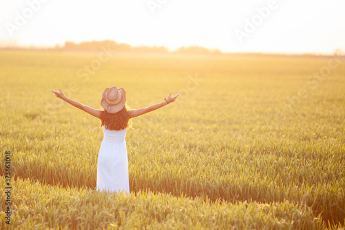 Mujer en el campo con los brazos abiertos hacia el sol del atardecer