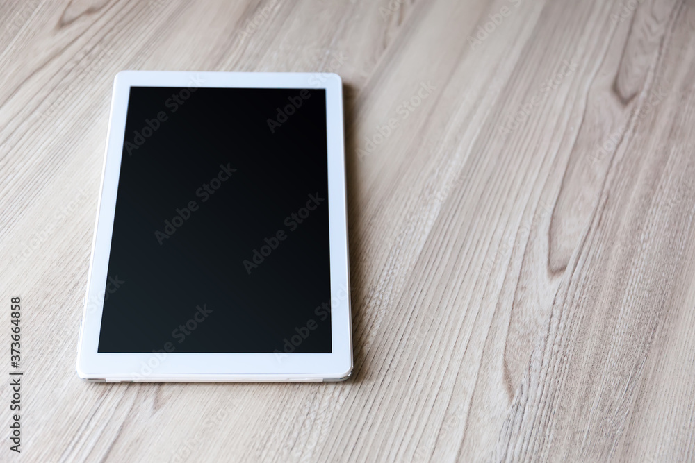 White tablet pc with empty screen on wood background White tablet pc with empty screen on wood background