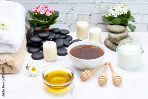 Bowls of honey and oil for skin treatment along with candles