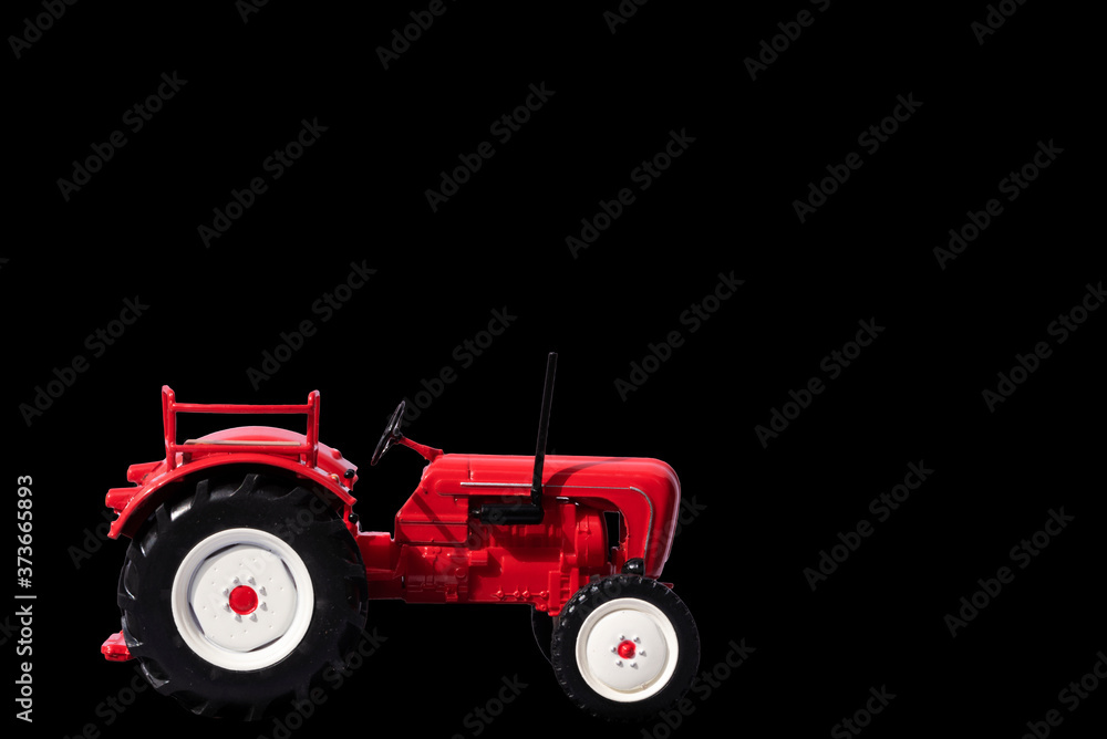 Naklejka premium Red toy tractor. Isolate on a black background. Selective focus.
