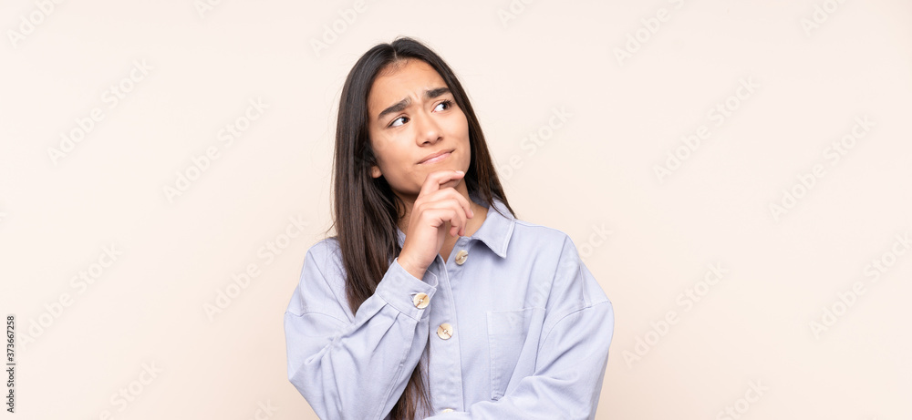 Young Indian woman isolated on beige background having doubts Young Indian woman isolated on beige background having doubts