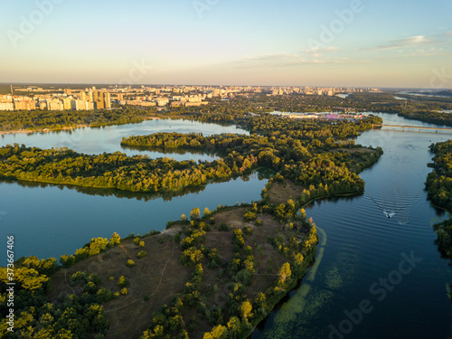 Aerial drone view. Bank of the Dnieper River in Kiev in the evening in the rays of the setting sun.