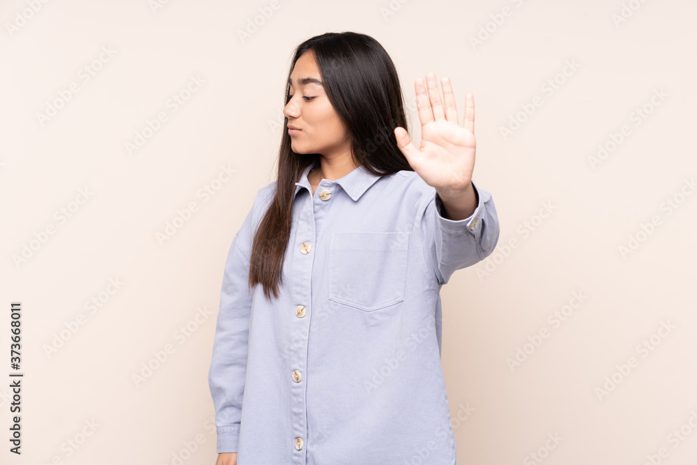 Young Indian woman isolated on beige background making stop gesture and disappointed Young Indian woman isolated on beige background making stop gesture and disappointed