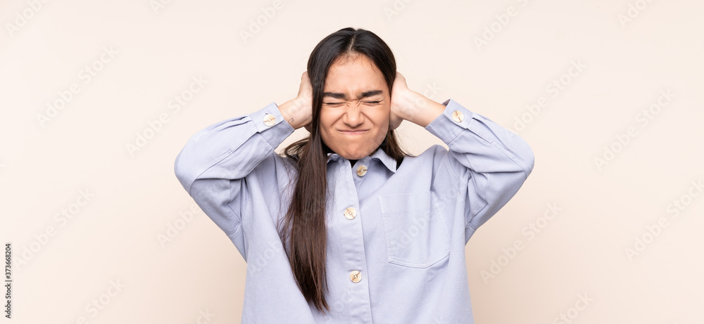 Young Indian woman isolated on beige background frustrated and covering ears Young Indian woman isolated on beige background frustrated and covering ears