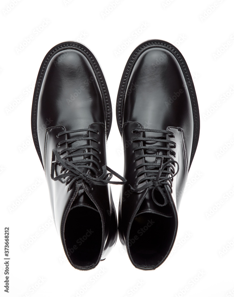 Classic black plain toe boots made of durable glossy leather with a small lace-up heel, isolated on a white background with a shadow. Top view. Classic black plain toe boots made of durable glossy leather with a small lace-up heel, isolated on a white background with a shadow. Top view.